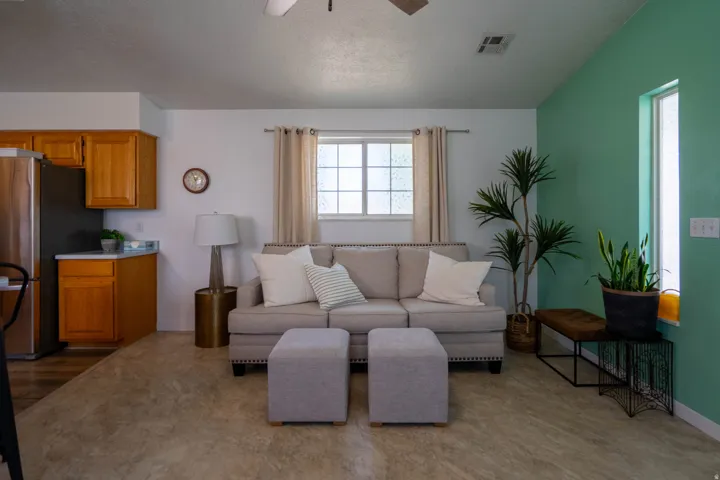 Open-concept living space featuring wood-finish flooring, a ceiling fan, and a kitchen area with wood cabinetry and stainless steel appliances