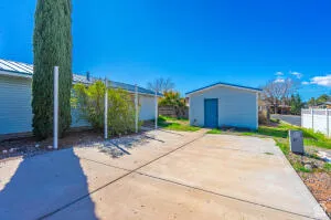 Concrete driveway with an independent storage shed featuring a blue door