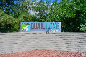 Quail Lake Estates community entry sign featuring a stone-look retaining wall and lush green landscaping