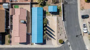 Property featuring a vibrant blue roof, a detached auxiliary structure, and a paved driveway