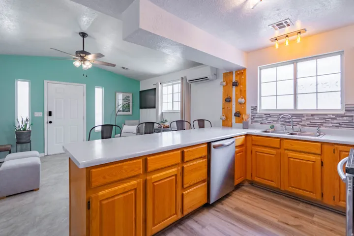 Open-concept kitchen featuring wood-finish cabinetry, light countertops, and a mosaic tile backsplash