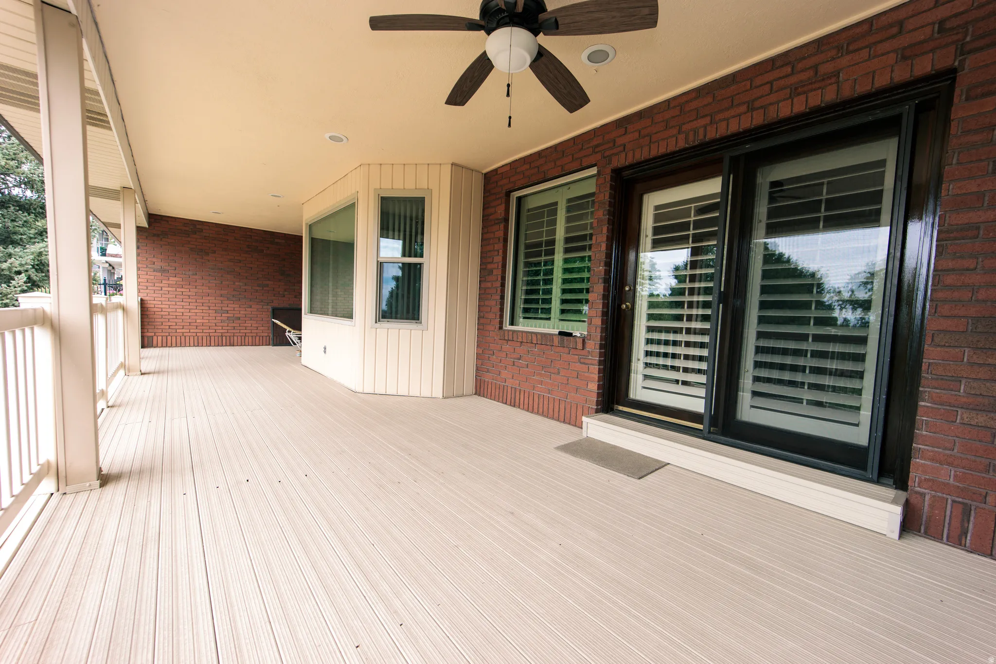 Expansive covered deck featuring composite decking, a ceiling fan, recessed lighting, and a bay window
