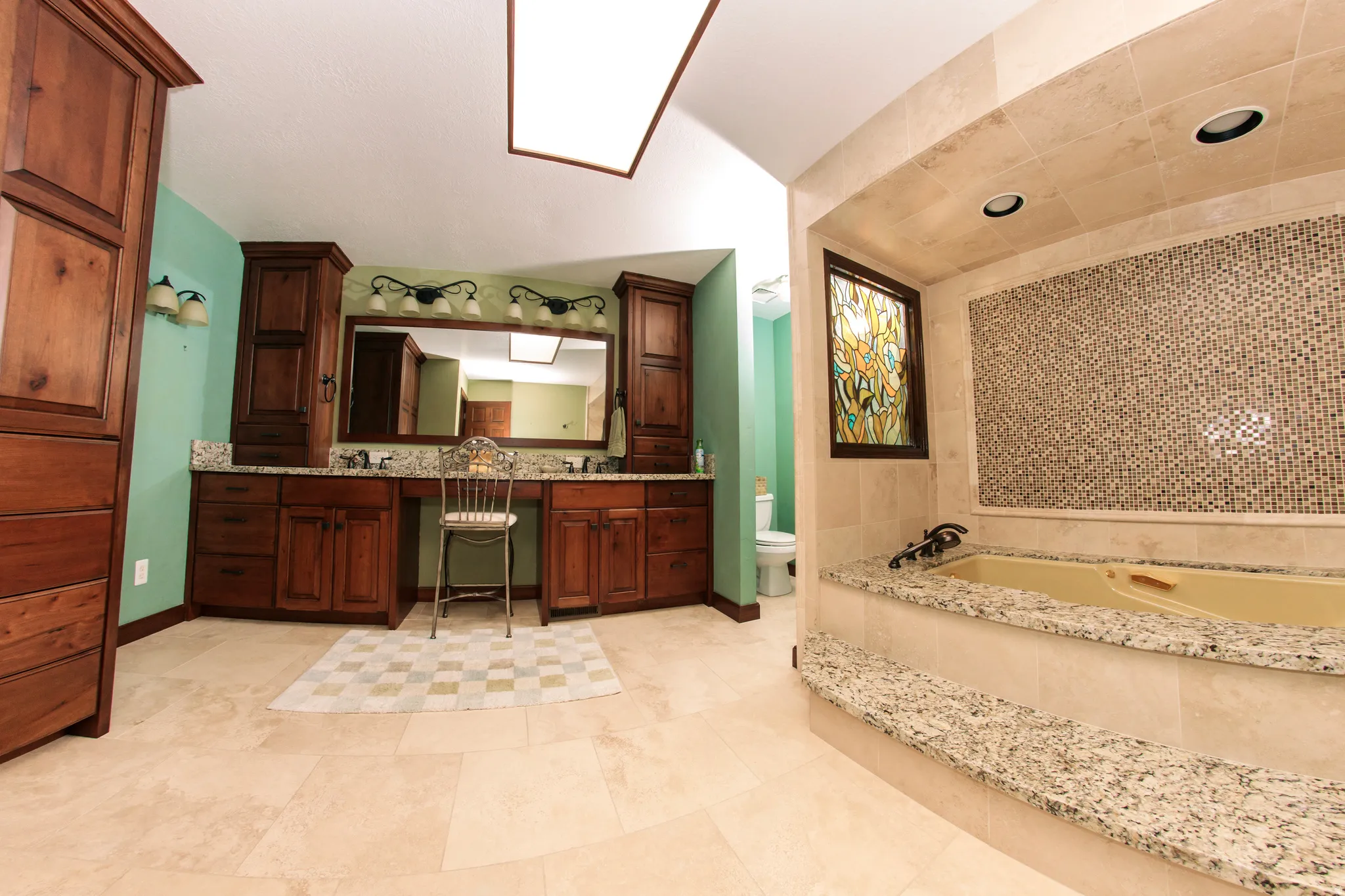 Spacious bathroom featuring a built-in soaking tub with granite surround and mosaic tile accent wall