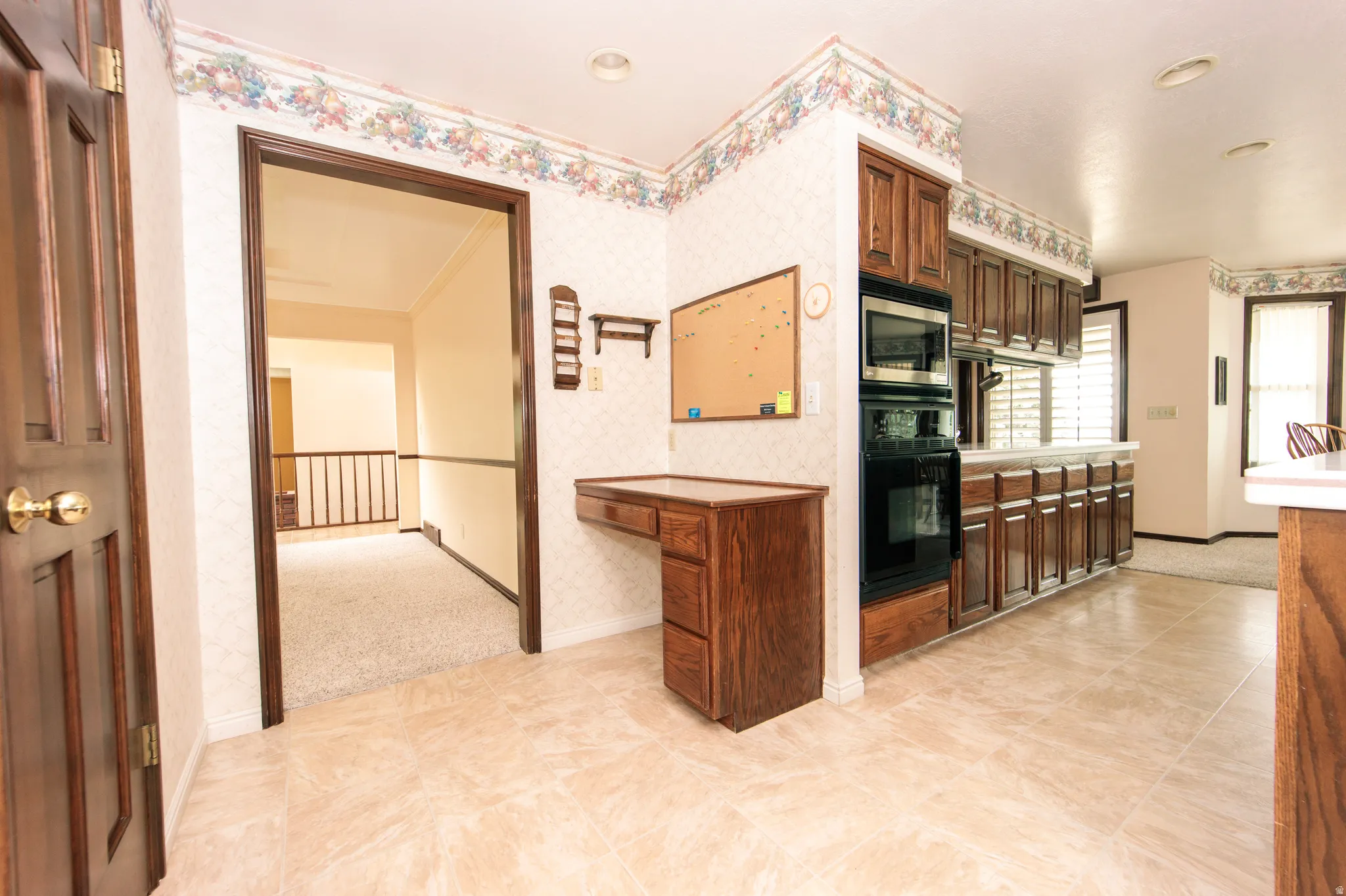 Kitchen area featuring wood cabinetry, built-in oven and microwave, and light-toned tile flooring
