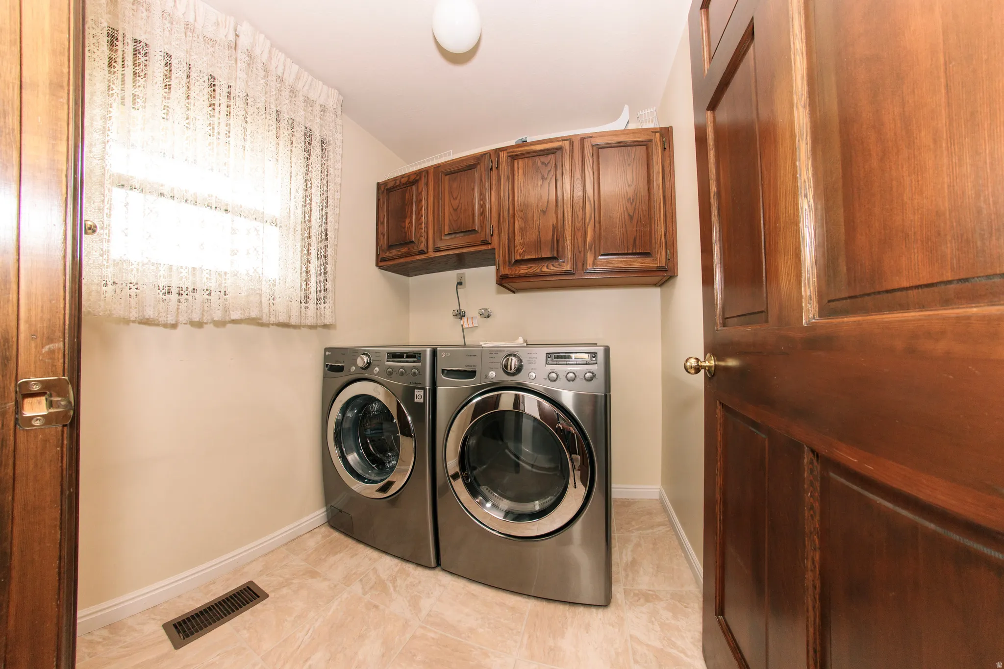 Utility space featuring a window, wood cabinetry, and tiled flooring