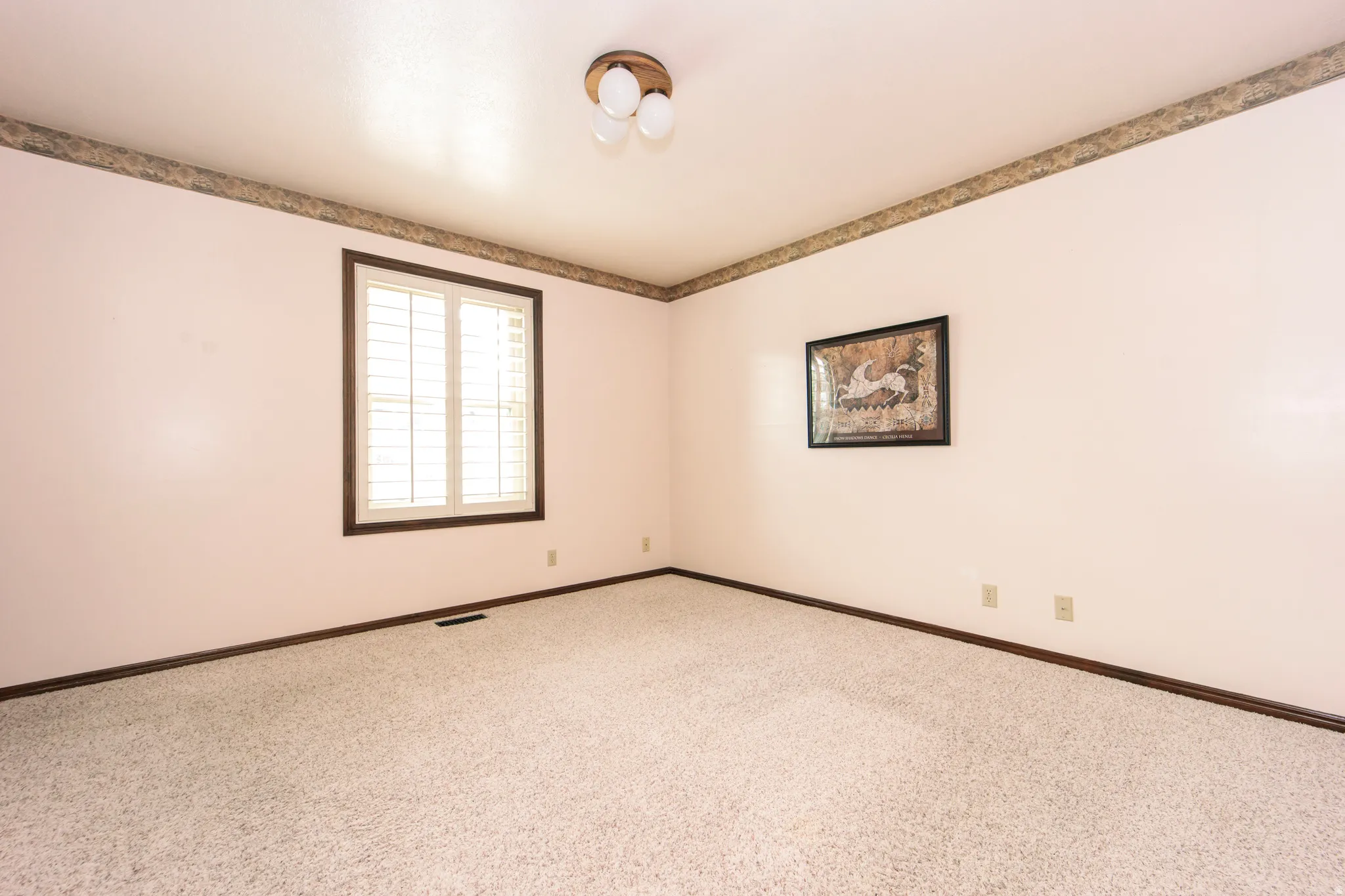 Room featuring carpet flooring and light-toned walls with a decorative border