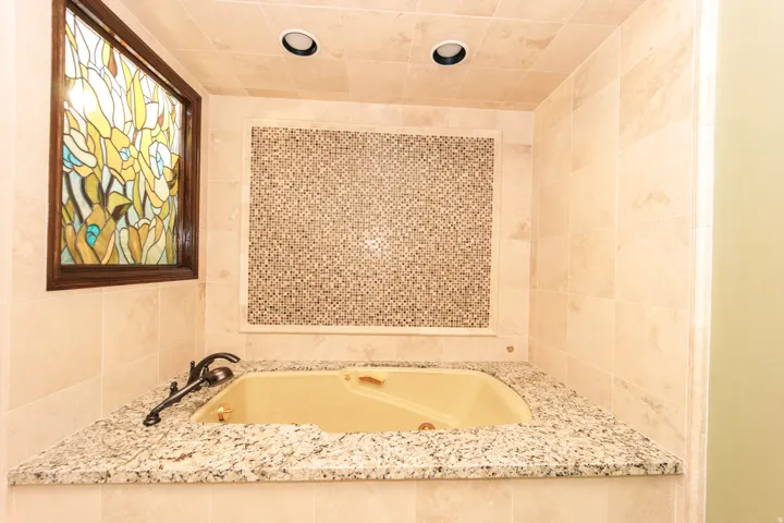 Corner soaking tub featuring a granite surround