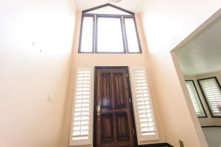 Grand entry featuring a dark wood paneled door with decorative carving and brass hardware