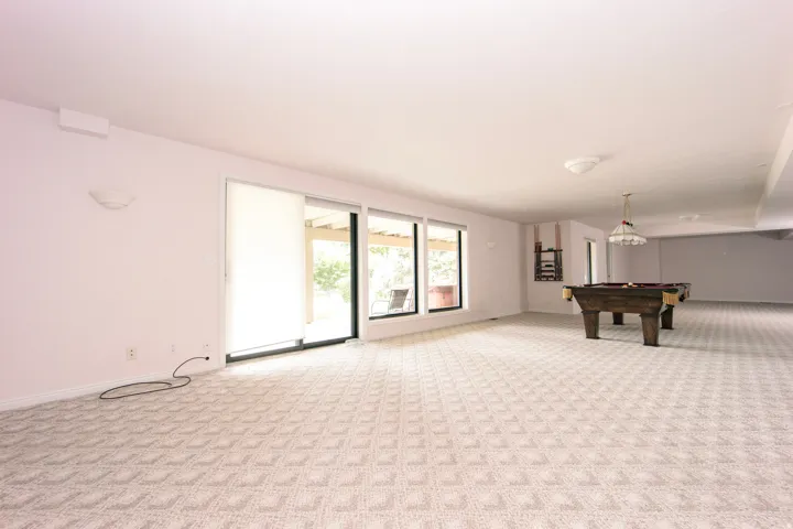 Spacious finished basement featuring patterned carpeting, multiple windows, and sliding glass doors