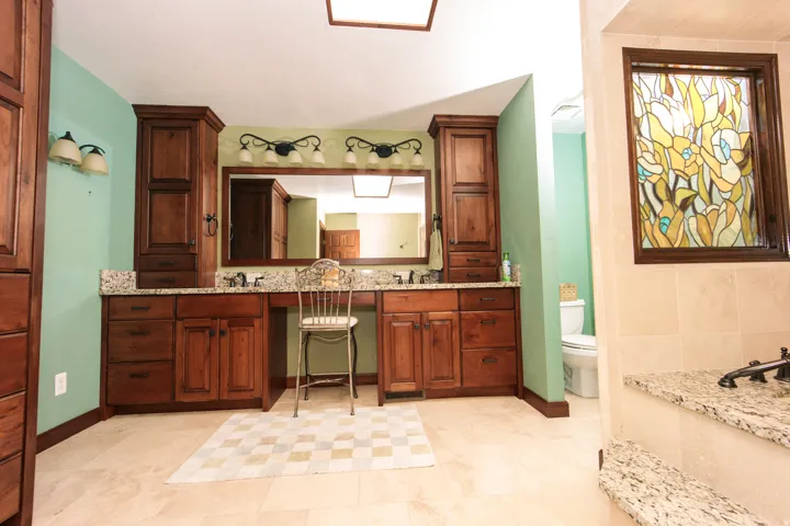 Expansive vanity area featuring dual sinks, rich wood cabinetry, and stone countertops