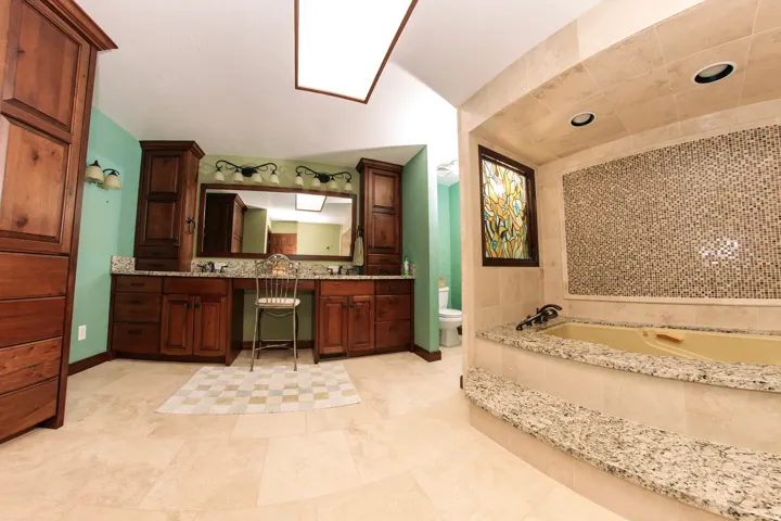 Spacious bathroom featuring a built-in soaking tub with granite surround and mosaic tile accent wall