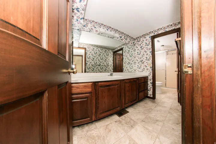 Bathroom featuring a spacious vanity with wood-finish cabinetry and a white countertop