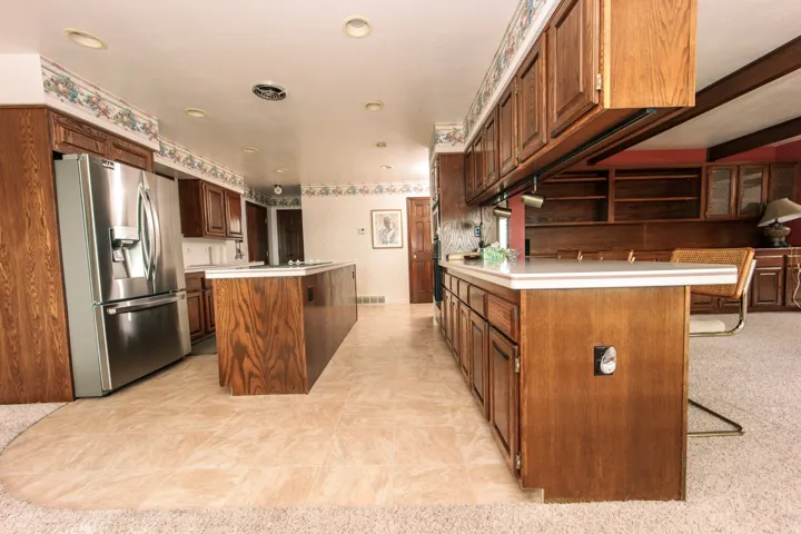 Expansive kitchen featuring a large central island, extensive wood cabinetry, and recessed lighting