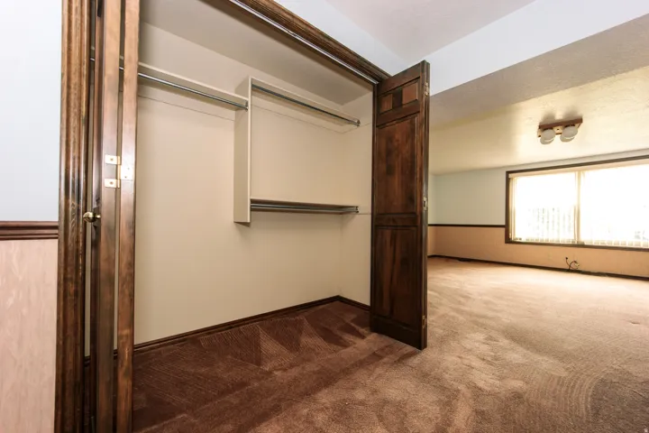 Built-in closet with bifold doors, featuring a multi-tiered hanging system and upper shelving