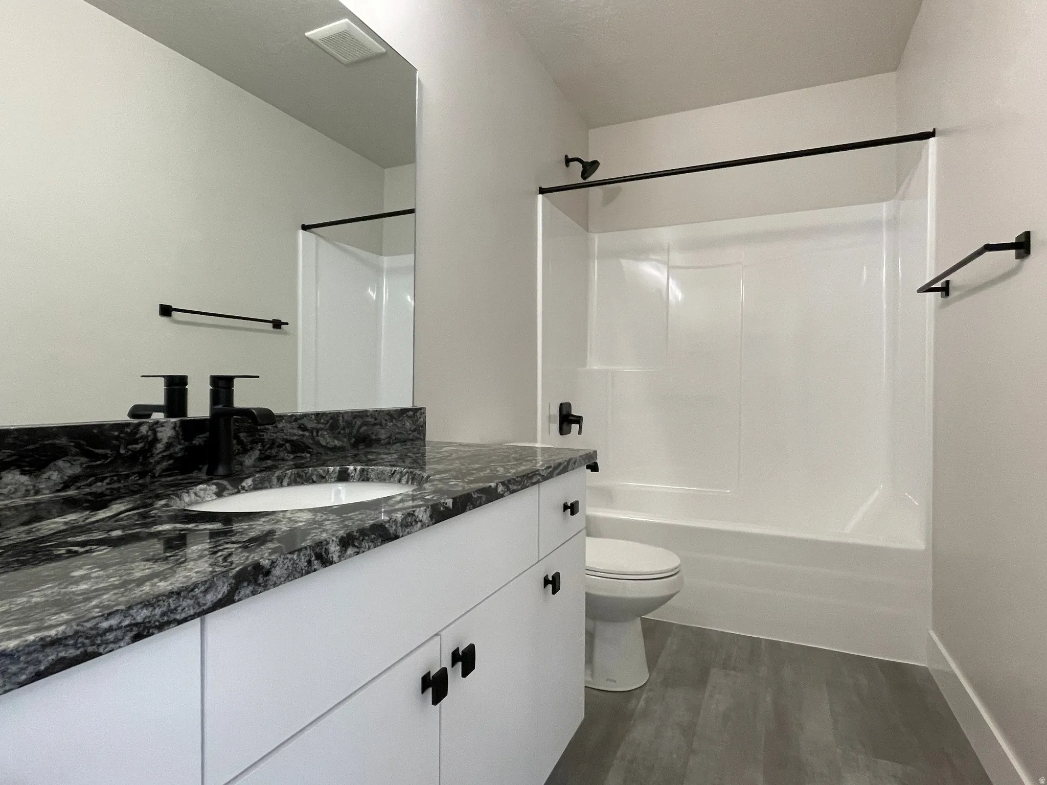 Bathroom featuring a white vanity with black granite countertop, undermount sink, and matte black hardware