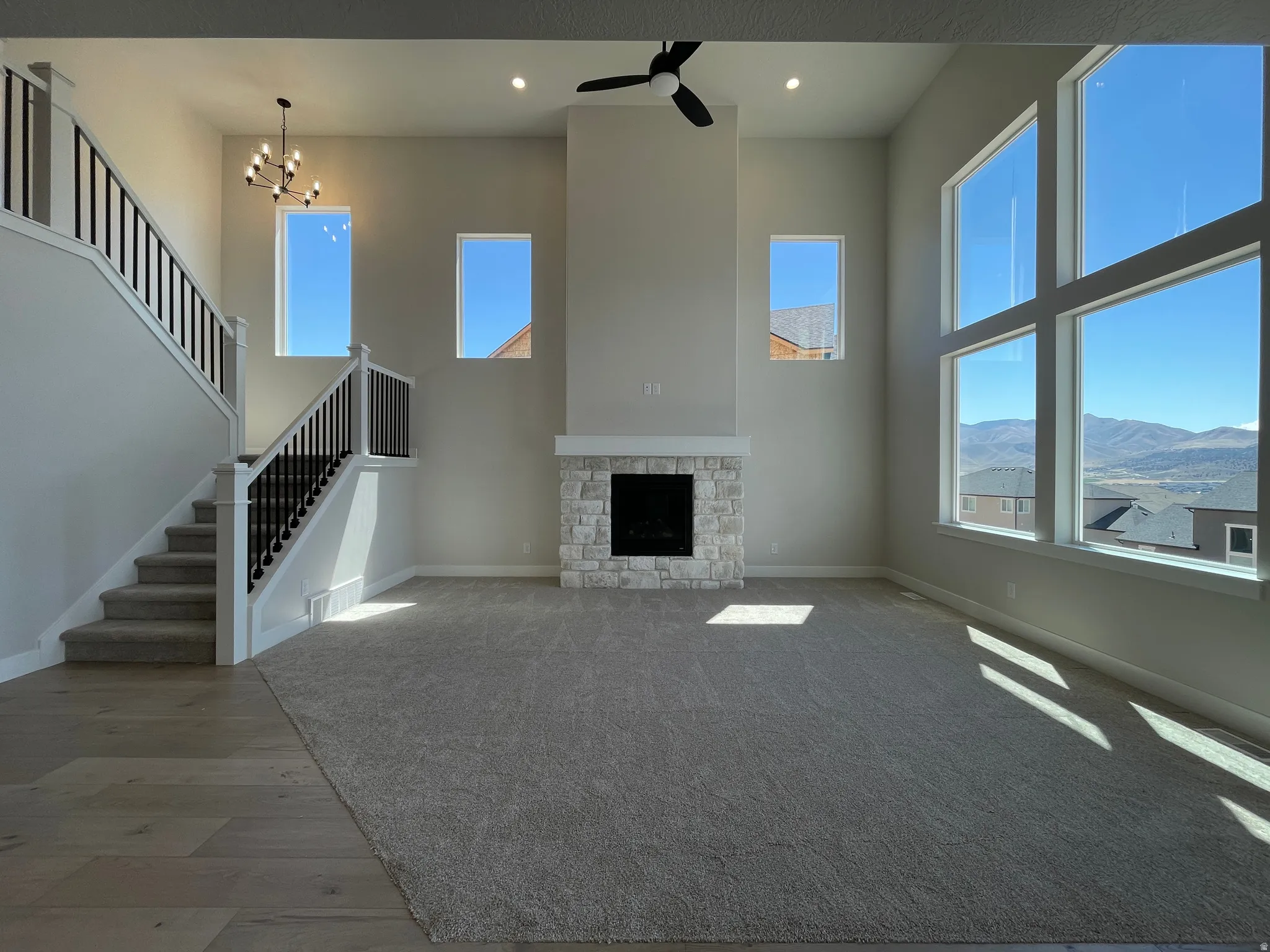 Great room featuring a floor-to-ceiling stone-clad fireplace, soaring ceilings, and expansive windows