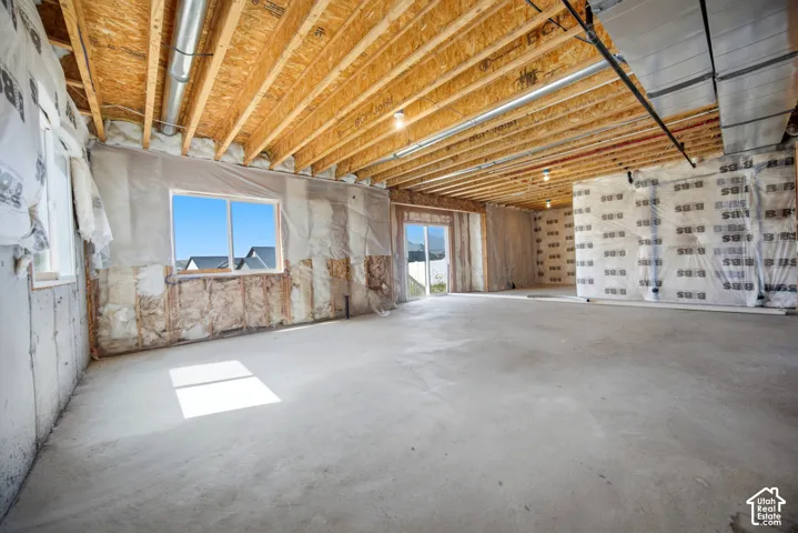 Unfinished lower level with concrete flooring, exposed wood joists, and exposed ductwork
