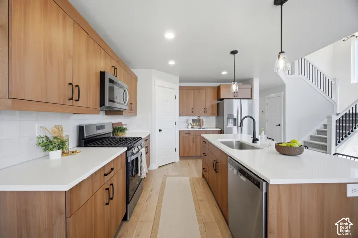 Well-appointed kitchen featuring wood-finish cabinetry, stainless steel appliances, white countertops, and a subway tile backsplash