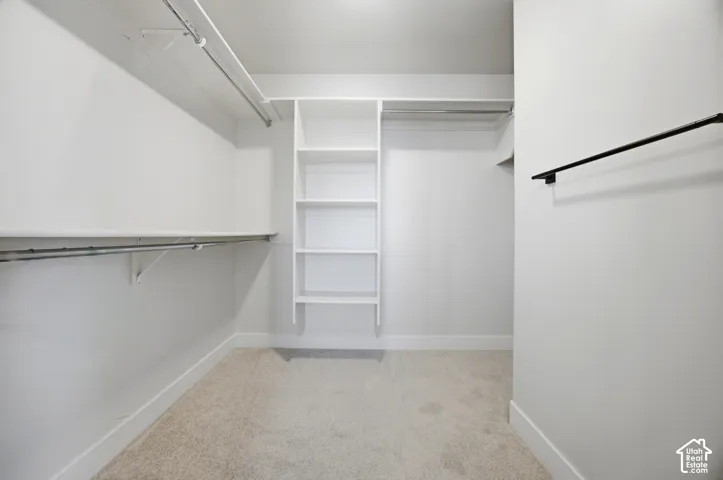 Walk-in closet featuring built-in shelving, hanging rods, and light-toned carpeting