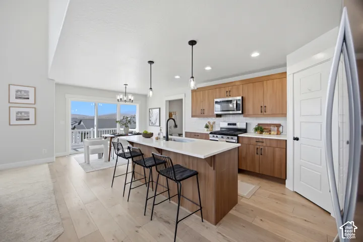 Kitchen featuring wood-finish cabinetry, stainless steel appliances, a white tile backsplash, and a center island with a light-toned countertop