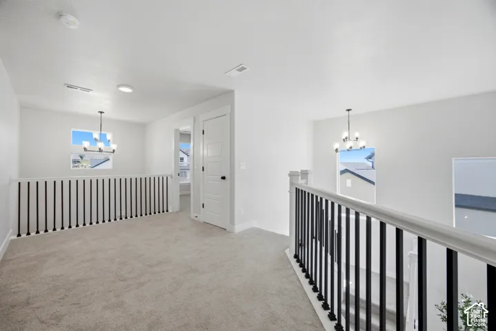 Carpeted landing with white walls, black metal balusters, and contemporary lighting fixtures