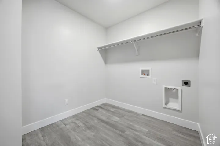 Dedicated laundry area featuring a wall-mounted drying rod, utility hookups, and wood-finish flooring
