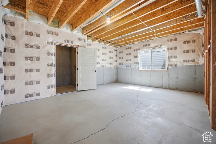 Unfinished basement with exposed ceiling joists, concrete floor, and a single window