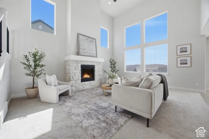 Spacious living area featuring a stone fireplace with a substantial mantel, high ceilings, and large windows