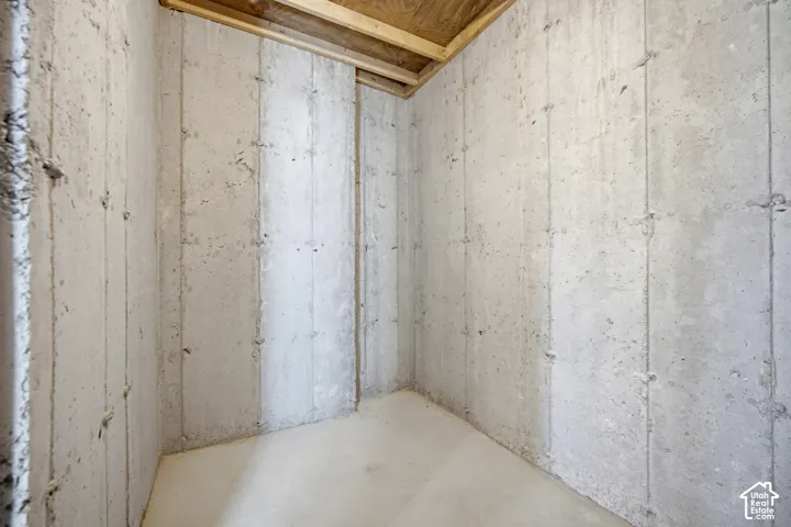 Unfinished space featuring concrete walls and flooring, with visible wood framing and plywood ceiling