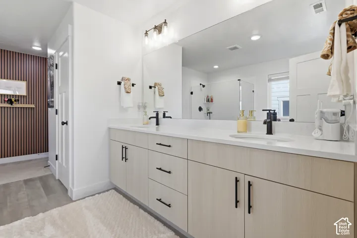 Spa-inspired primary bathroom featuring dual vanities with wood-finish cabinetry, white quartz countertops, and matte black hardware