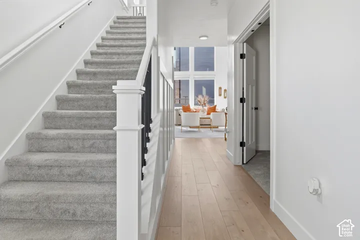 Carpeted staircase with white newel post and dark balusters