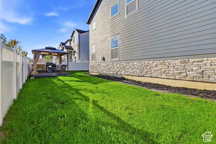 Expansive lawn area, white privacy fencing, and a built-in deck with a gazebo
