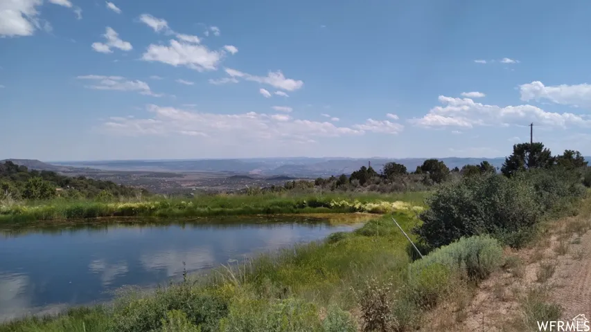 Expansive natural pond reflecting the sky, surrounded by native grasses and brush