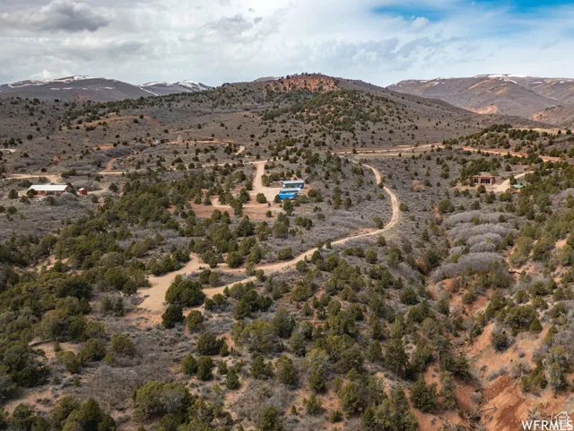 Expansive land parcel featuring natural desert flora, multiple dirt roads, and distant mountain ranges with snow-capped peaks