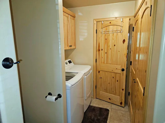 Laundry area featuring overhead cabinetry, tile flooring, and solid wood doors
