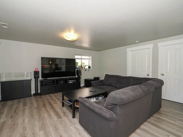 Wood-finish flooring, light gray walls, built-in ceiling light fixture, and white interior doors with trim