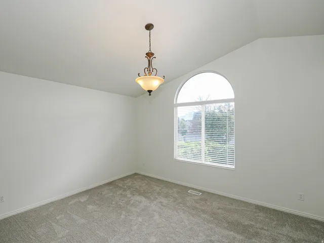 Arched window with blinds, vaulted ceiling, neutral wall paint, and gray carpet flooring