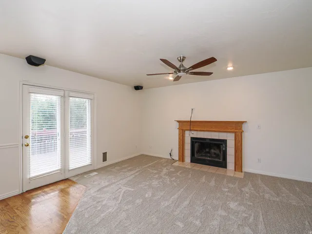 Fireplace with wood mantle and tile surround, ceiling fan with integrated lighting, recessed lighting, and glass panel French doors