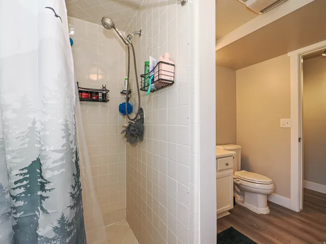 White tiled shower with a handheld shower fixture
