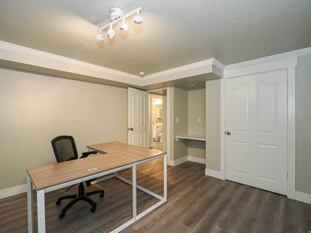 Wood-finish flooring with track lighting and crown molding