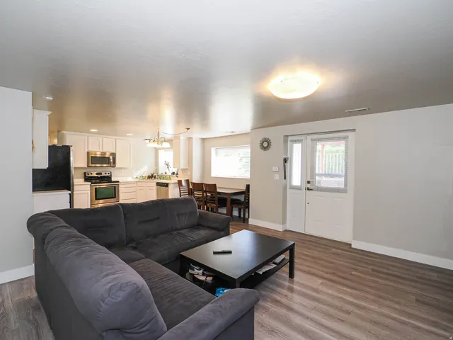 Open-concept living space with wood-finish flooring, white kitchen cabinetry, stainless steel appliances, and a dining area