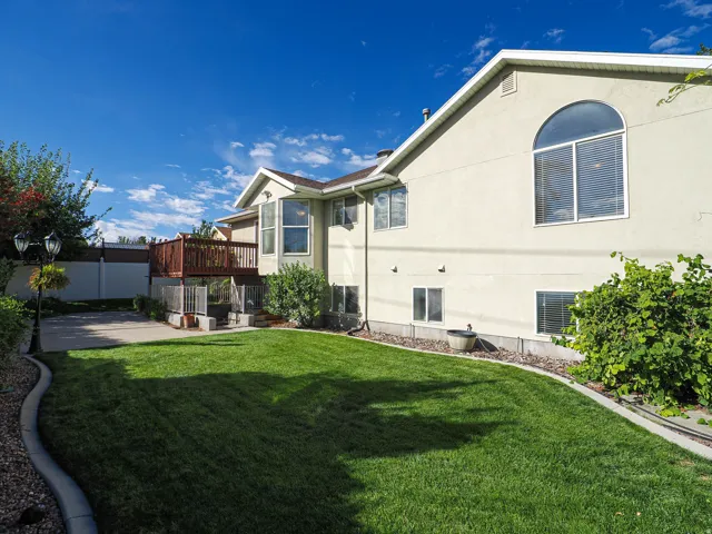 Spacious backyard featuring a manicured lawn, concrete curbing, and mature landscaping