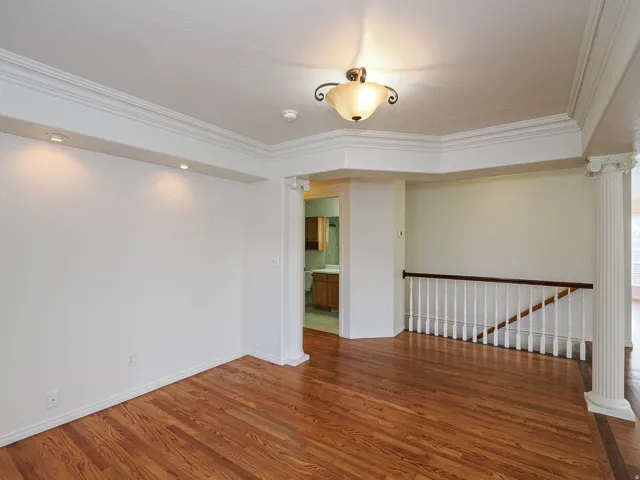 Hardwood flooring, decorative ceiling trim, recessed wall lighting, column architectural detail, and a built-in staircase balustrade