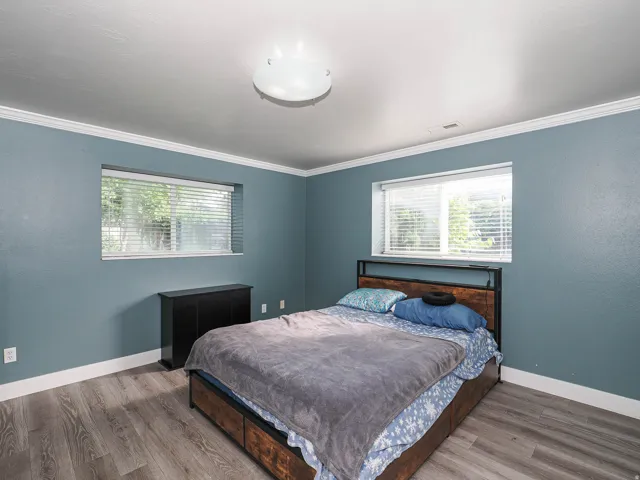 Wood-finish flooring, crown molding, and two windows with blinds