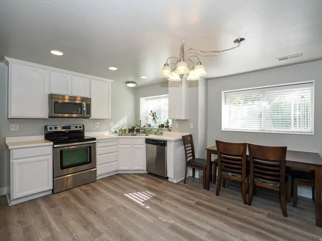 Kitchen featuring stainless steel appliances, white cabinetry, light countertops, wood-finish flooring, and recessed lighting
