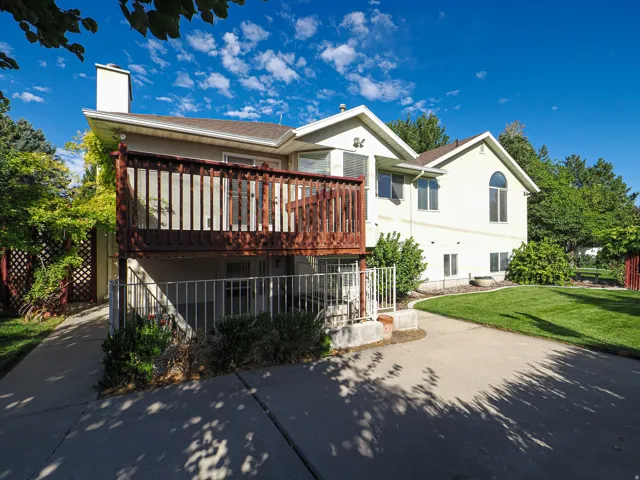 Expansive concrete patio, wood deck, well-maintained lawn, and mature landscaping