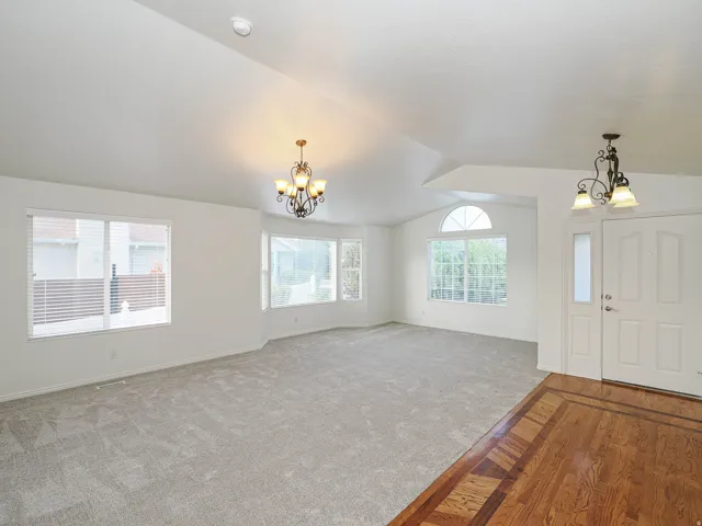 Vaulted ceilings, a decorative chandelier, expansive windows, arched transom window, and hardwood flooring with inlay