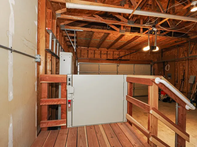 Equipped garage featuring a powered lift system, wood decking, and a wood handrail