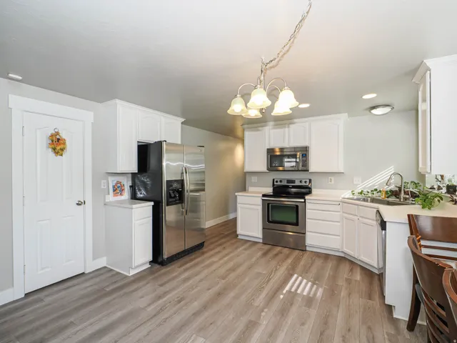 Kitchen featuring wood-finish flooring, white cabinetry, stainless steel appliances, and an undermount sink