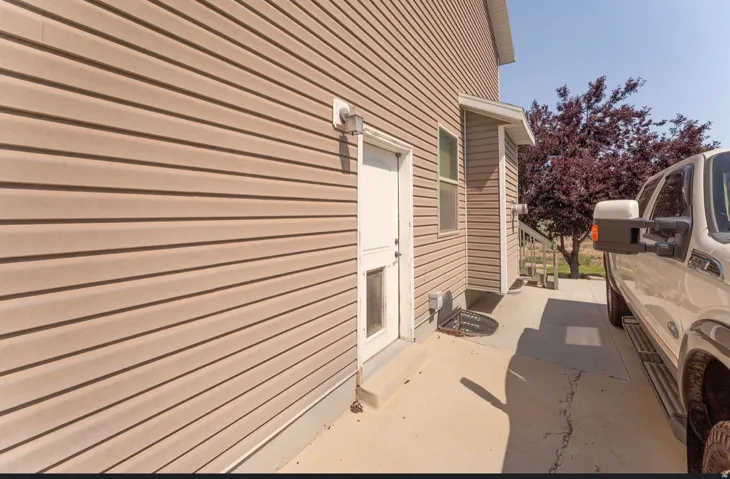 Tan horizontal siding exterior with a white entry door and covered porch